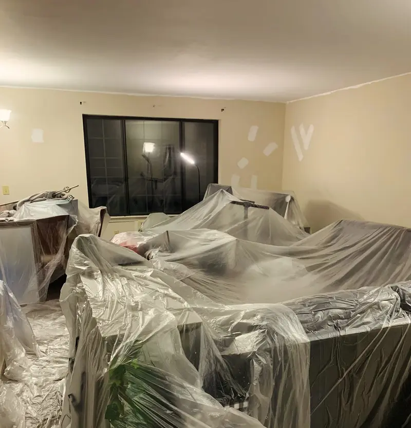 Living room furniture and floor fully covered in plastic before painting