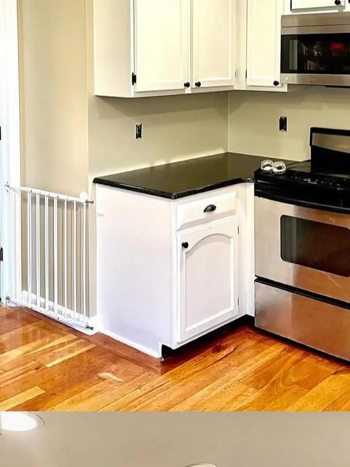 Kitchen cabinets painted white next to a stainless steel range