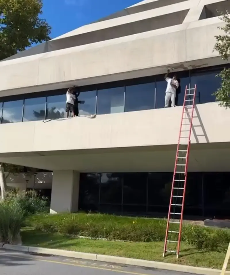 Painters on a ladder restoring the facade of a commercial office building