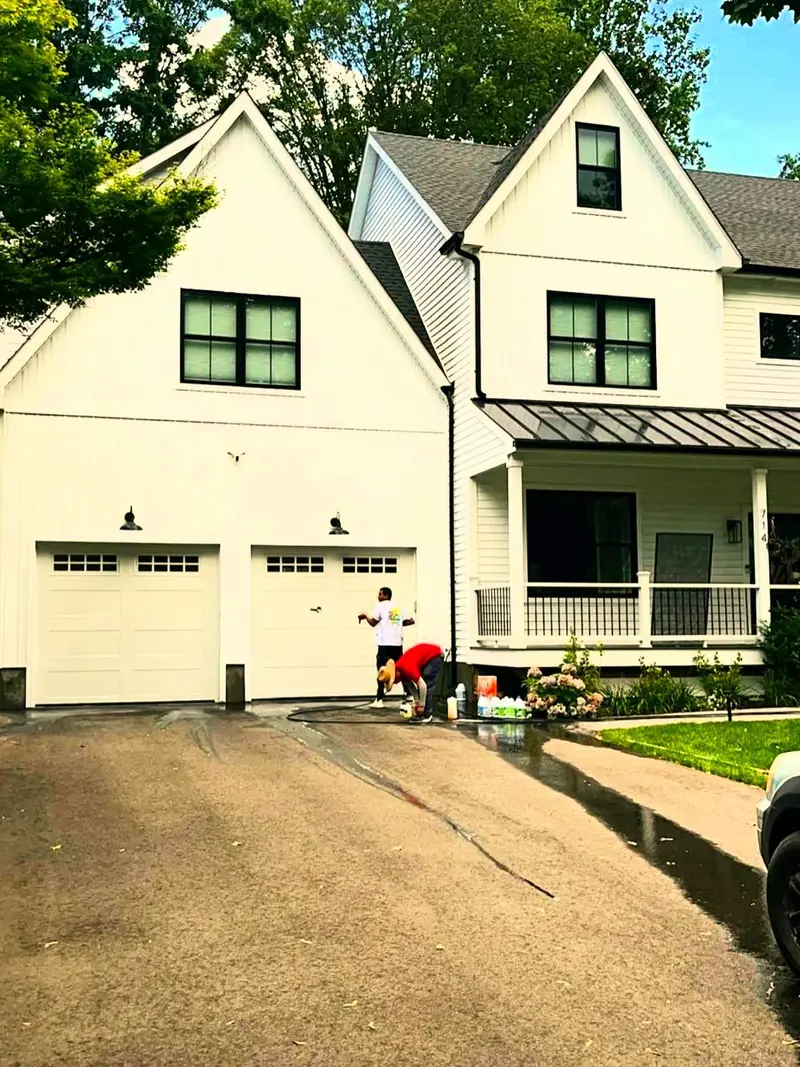 Crew painting the exterior of a white two-story farmhouse with black windows