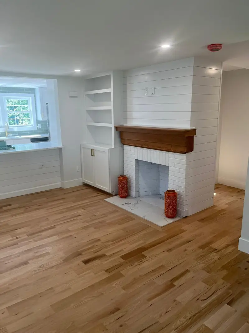 Living room after interior painting, with a white shiplap fireplace wall and built-in shelves
